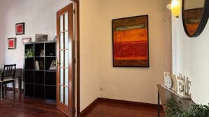 A room with a wooden floor, a bookshelf, a door, and a wall with a painting. - "Domus Font" - Apartment in Plaça de la Font (Tarragona)