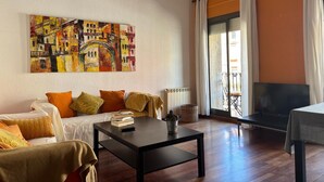 A living room with a sofa, a coffee table, a painting, and a TV. - "Domus Font" - Apartment in Plaça de la Font (Tarragona)