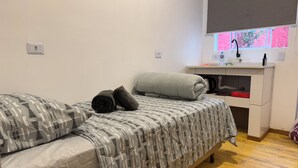Une petite chambre à coucher, bien rangée, avec un lit, des oreillers, une table de chevet et une fenêtre donnant sur un beau paysage.