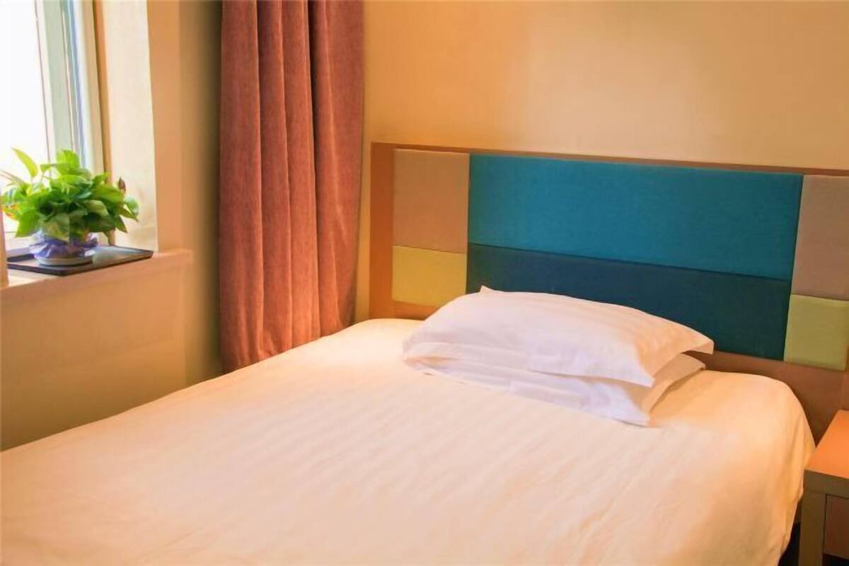 A neatly made bed with white linens and a headboard with a teal and beige color scheme.