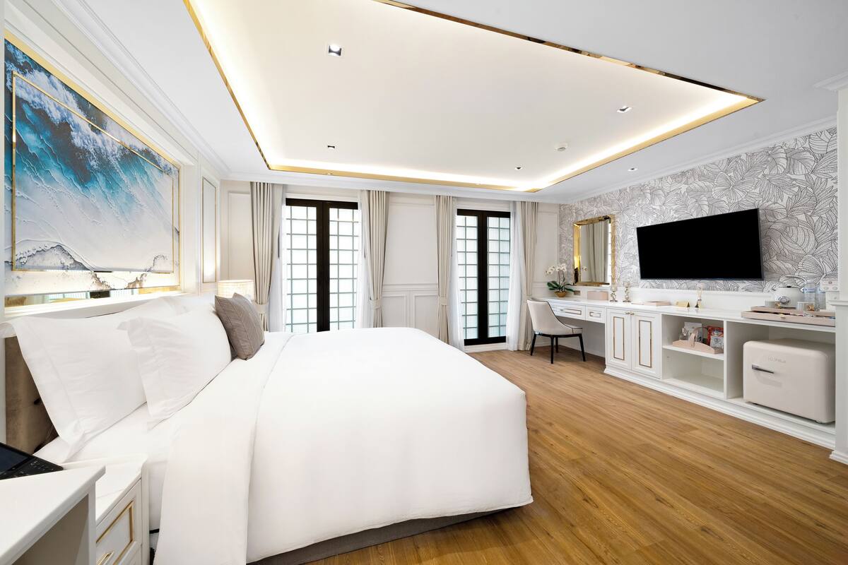 Una habitación de hotel moderna con una cama grande, un escritorio, un televisor de pantalla plana y una tocador con espejo.