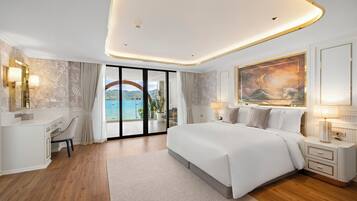 Un dormitorio moderno con una cama grande, un escritorio y vista al mar a través de un ventanal.