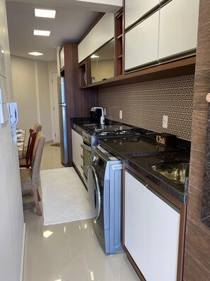 A modern kitchen with a gas stove, built-in oven, and a dishwasher. - Resid. Clube Mar Grosso-Laguna - LAG605 (Laguna)
