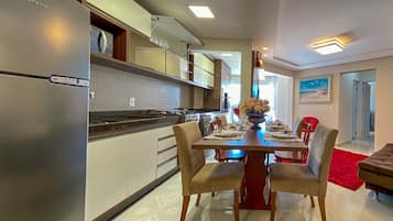 Une cuisine moderne avec un réfrigérateur en acier inoxydable, un coin repas avec une table et des chaises en bois, et un tapis rouge.