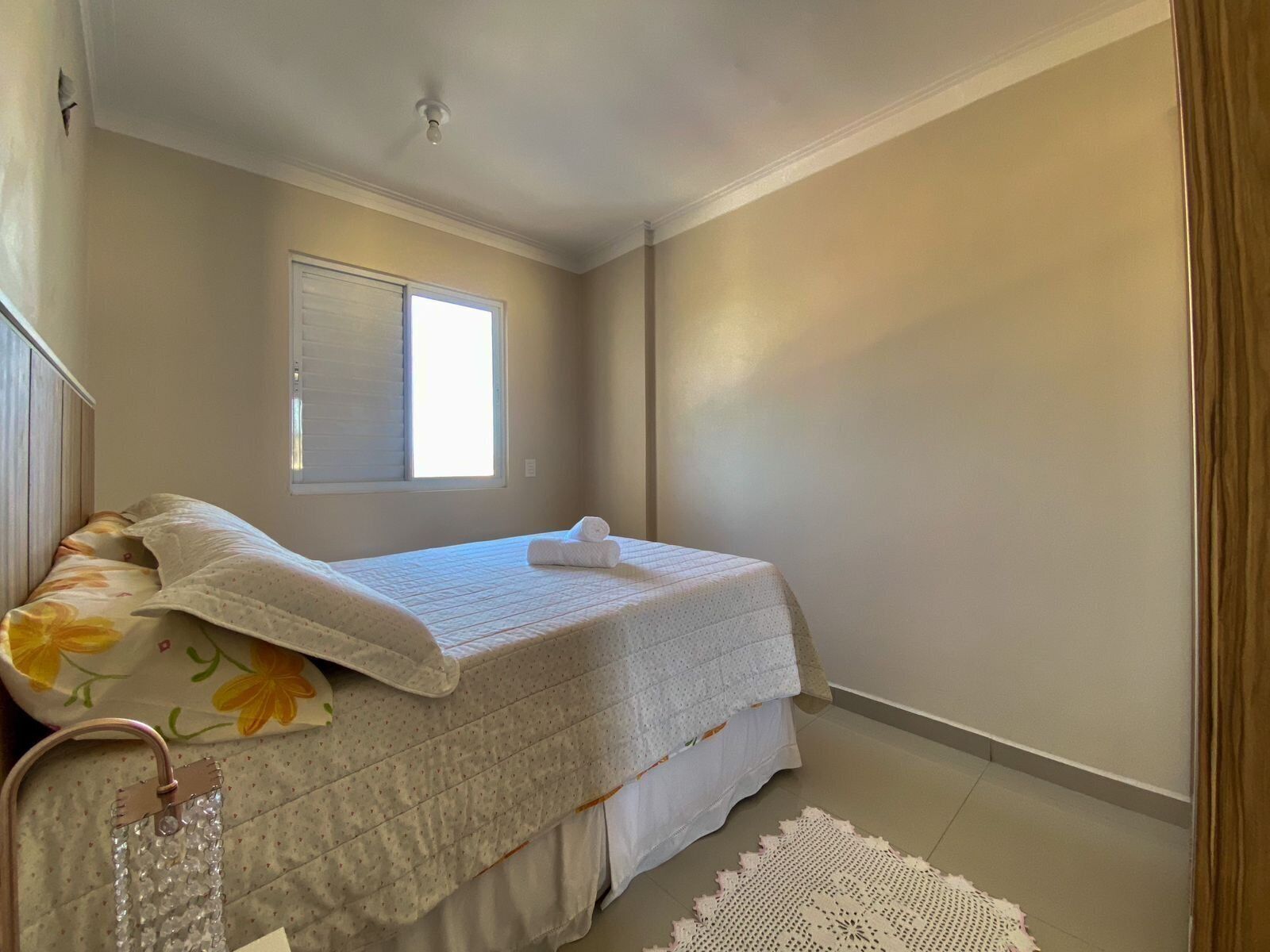 Un dormitorio con cama, ventana y lámpara en el techo.