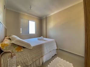 A bedroom with a bed, a window, and a ceiling light. - Resid. Clube Mar Grosso-Laguna - LAG605 (Laguna)