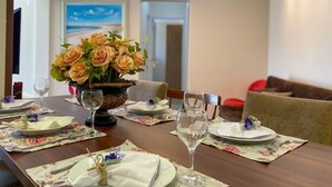 Ein Esstisch, gedeckt mit floralen Platzsets, einer Blumenvase und Weingläsern.