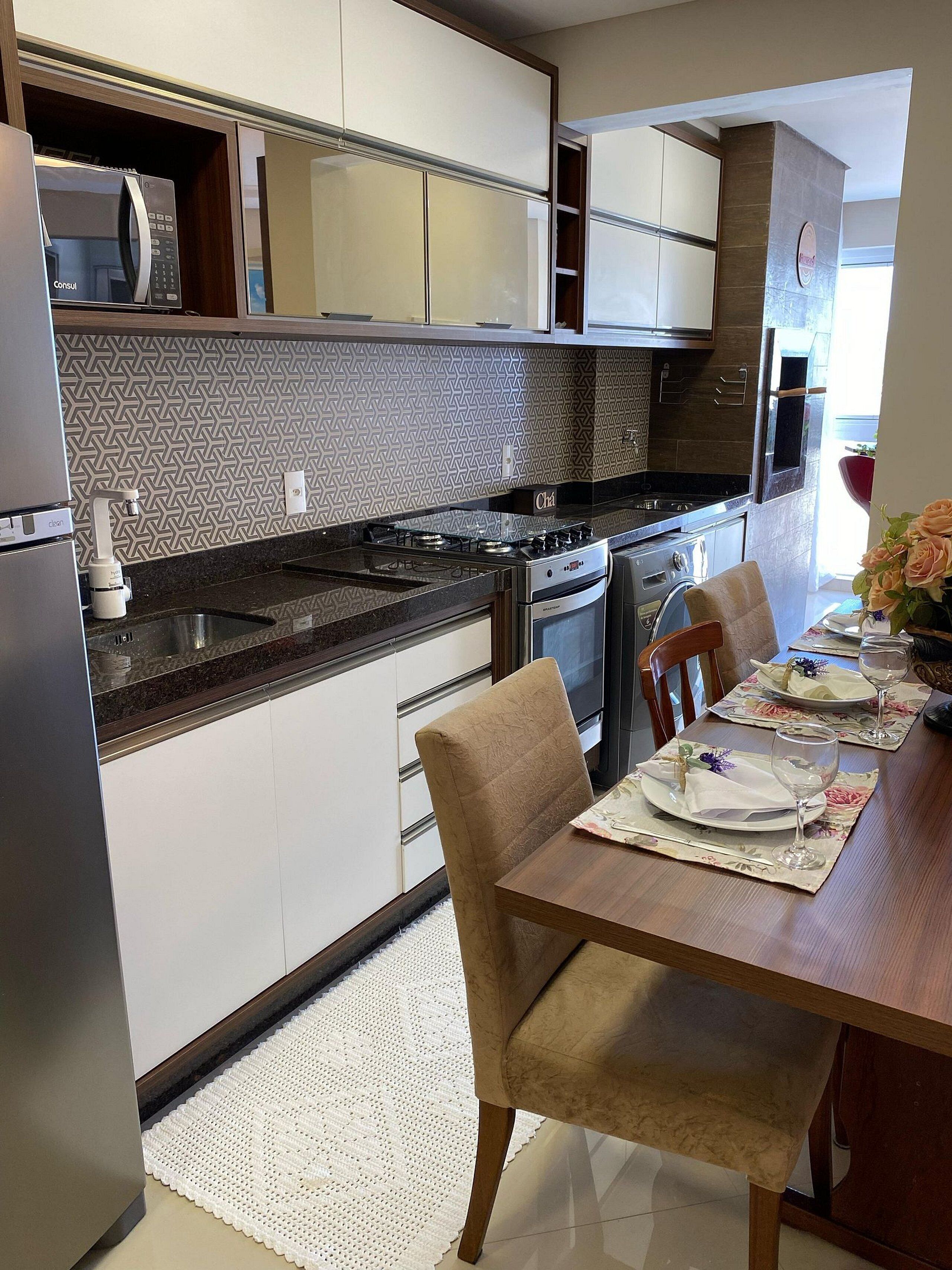 Une cuisine moderne équipée d’un four à micro-ondes, d’une cuisinière et d’un four encastrés. On y trouve une table à manger avec des chaises et un set de table.