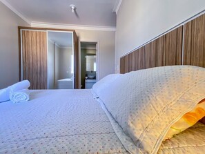 Una habitación de hotel con una cama, baño y espejo.