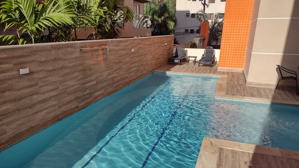 Une piscine à l’eau d’un bleu cristallin, entourée d’un mur en bois et dotée d’un sol carrelé.