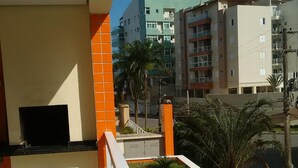 Un balcon équipé d’un téléviseur à écran plat, avec des murs recouverts de carreaux orange et un petit espace aménagé en jardin.