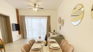 A dining area with a round table set for four, surrounded by cushioned chairs. A ceiling fan is visible above the table. - Hard Rock Punta Cana Coral Bay II (Punta Cana)