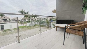 A balcony with a view of a residential area, a sofa, and a chair. - Hard Rock Punta Cana Coral Bay II (Punta Cana)