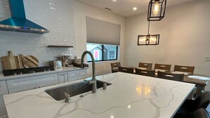 Una cocina moderna con una isla grande, electrodomésticos de acero inoxidable y una ventana con vistas.