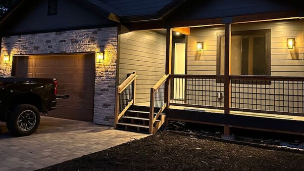 A two-story house with a stone foundation, a garage, and a covered porch with steps.