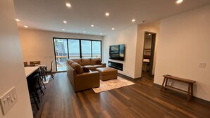 A modern living room with a sofa, ottoman, and a TV mounted on the wall.