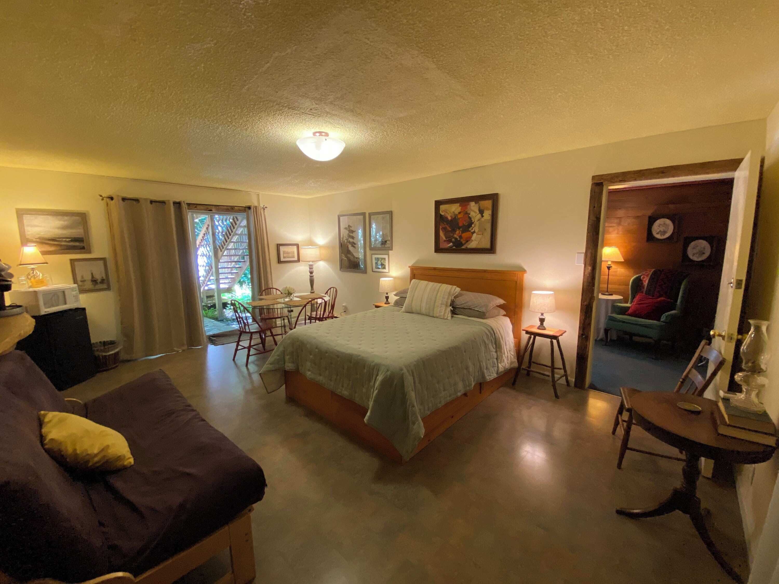A bedroom with a bed, a sofa, a dining table, and a chair.