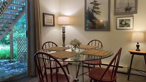 A dining area with a glass table, four wooden chairs, two wall-mounted lamps, and framed artwork. - Manitou Lodge (Forks)