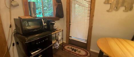 A compact kitchen with a microwave, oven, and a small table.