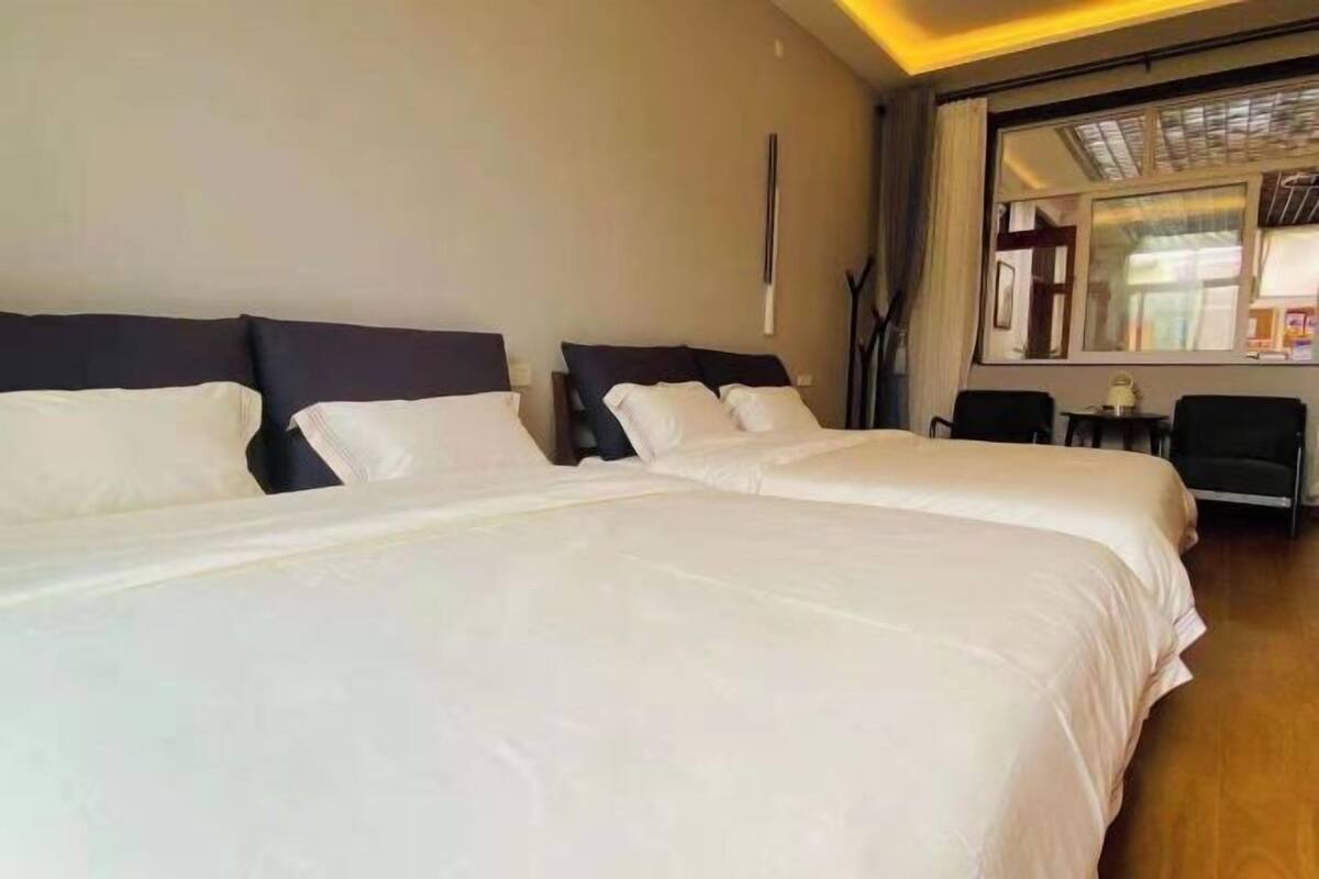 A hotel room with two beds, a large window, and a small table with chairs.