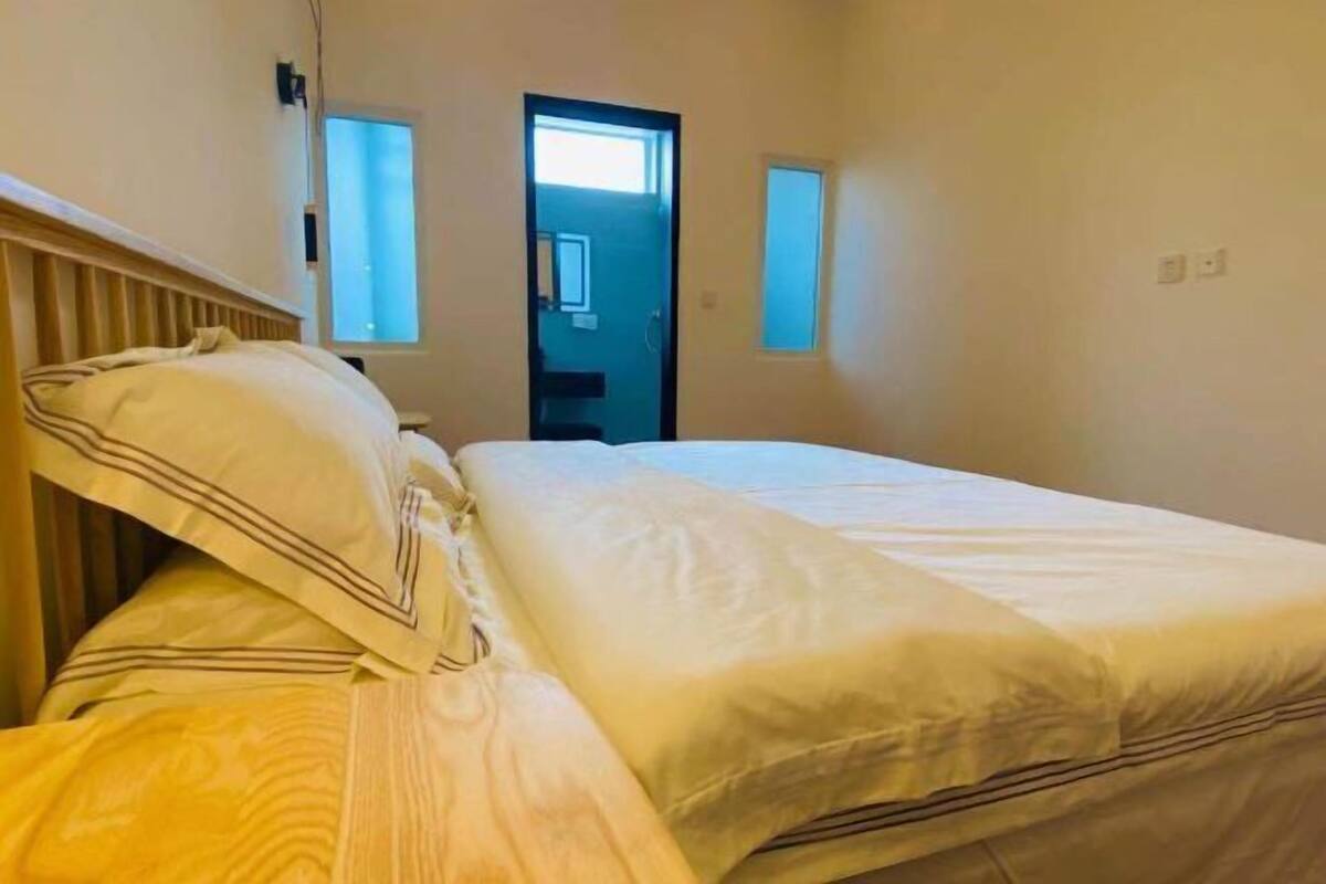 A bedroom with a bed, a window, and a door.