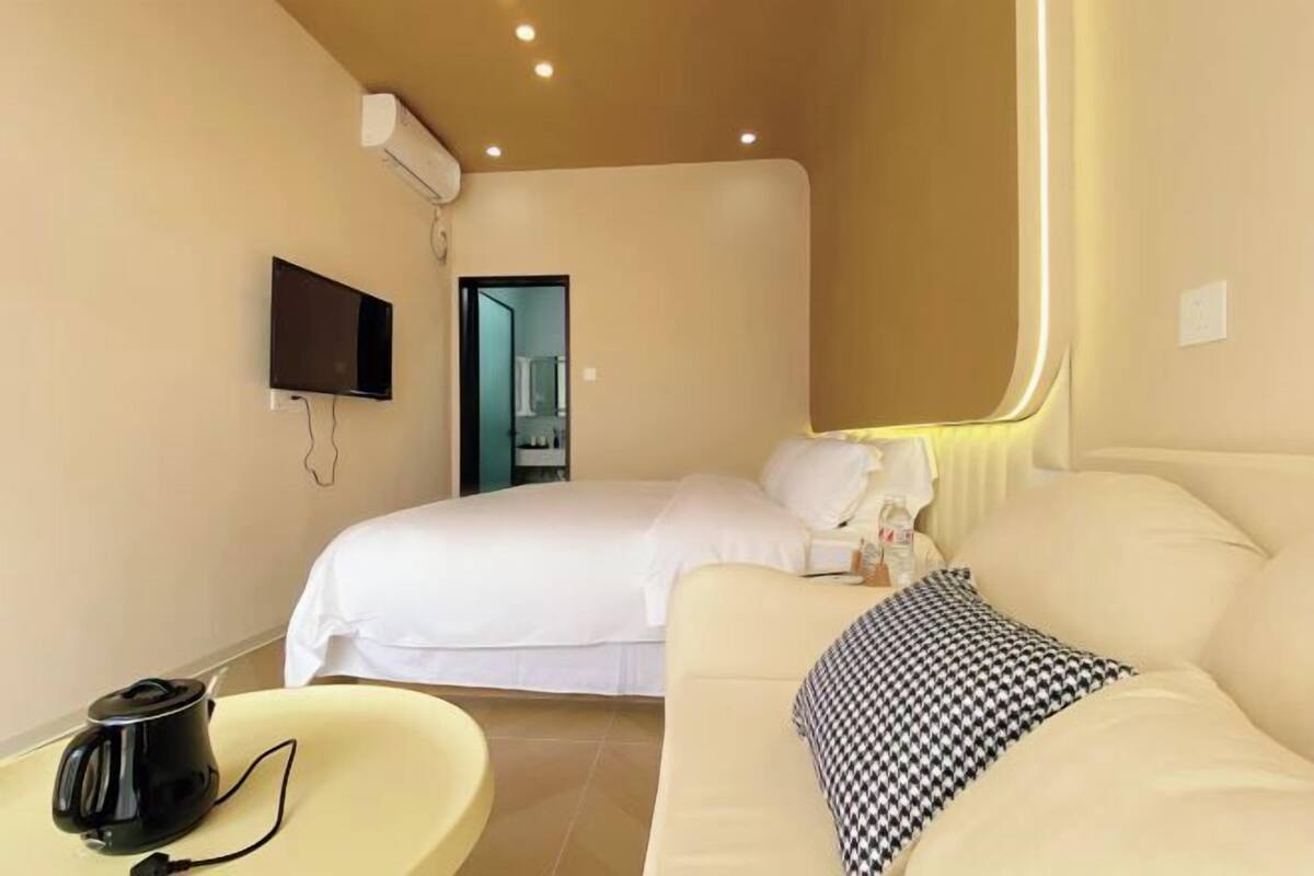 A hotel room with a bed, a sofa, a TV, and a coffee maker.