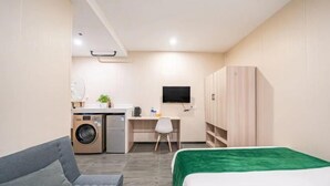 A compact hotel room with a bed, a desk, a chair, a washing machine, and a TV. - Shanghai Tianyang Hotel (Huangxing Road Subway Station) (Shanghai)