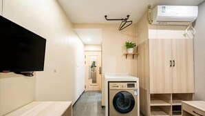A laundry room with a washing machine, a TV, and wooden cabinets. - Shanghai Tianyang Hotel (Huangxing Road Subway Station) (Shanghai)