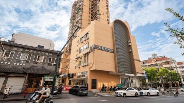 A multi-story building with a curved facade, likely a hotel or office building, with a busy street in front. - Shanghai Tianyang Hotel (Huangxing Road Subway Station) (Shanghai)