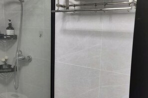 A shower area with a glass door, a handheld showerhead, and a soap dispenser on a shelf. - Shanghai Tianyang Hotel (Huangxing Road Subway Station) (Shanghai)
