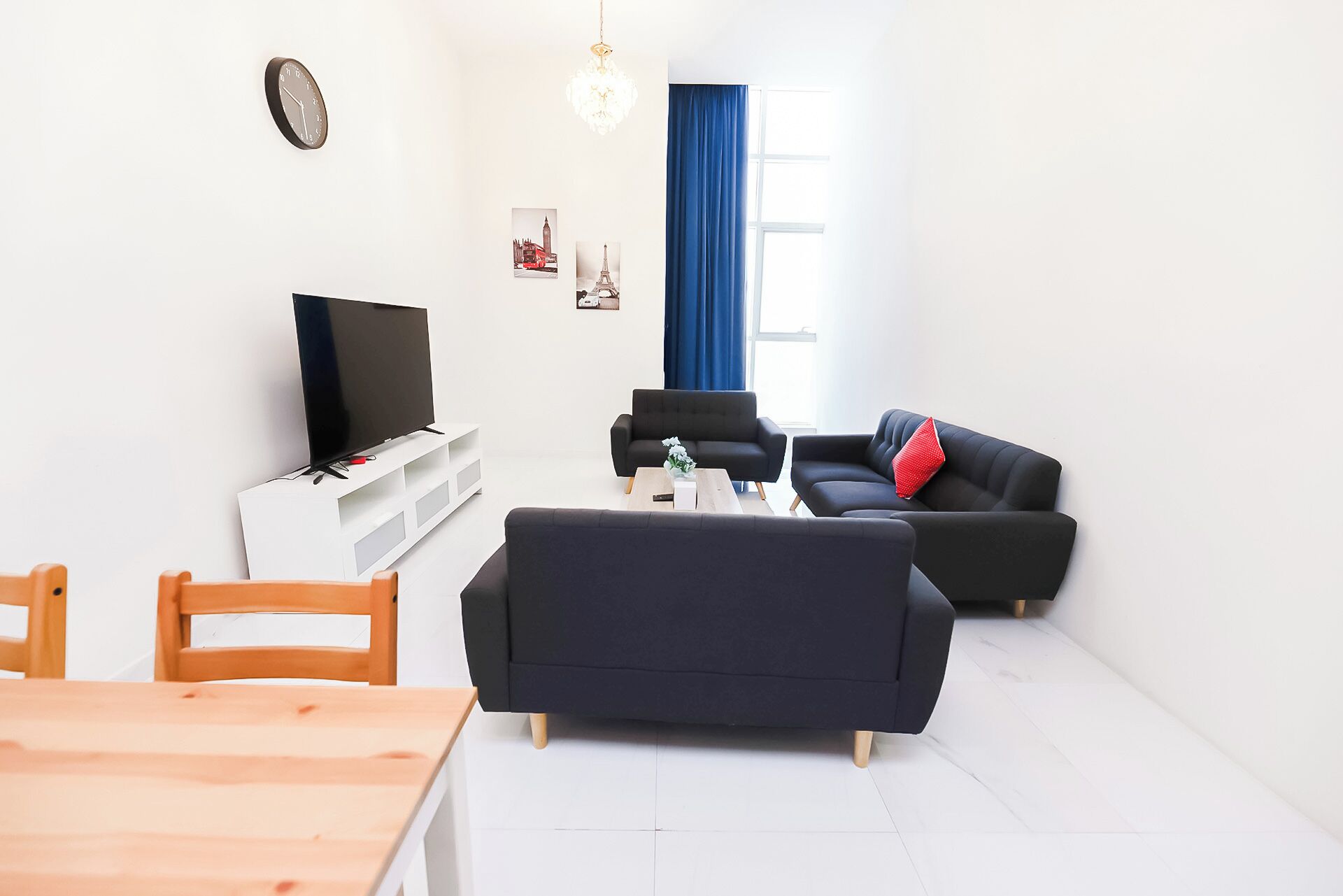 A modern living room with a flat-screen TV, two sofas, a coffee table, and a dining table.