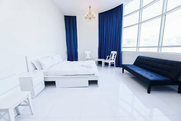 A modern bedroom with a bed, a sofa, a chair, and a desk.