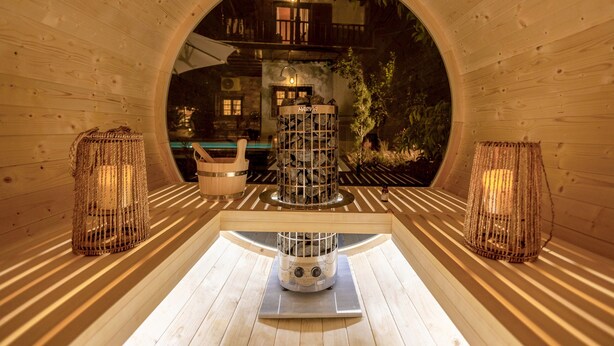 Interior de madera con una estructura circular central, bancos de madera y dos faroles colgantes.