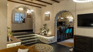 Una sala de estar moderna con una escalera, paredes de piedra y una zona de bar.