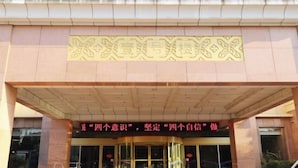 A building entrance with a large decorative sign above the doors and a slogan in Chinese characters.