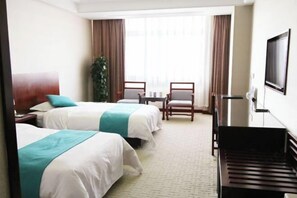 Ein Hotelzimmer mit zwei Betten, einem Schreibtisch, einem Stuhl, einem Fernseher und einem Klavier.