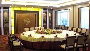 A conference room with a round table, chairs, and a floral centerpiece.