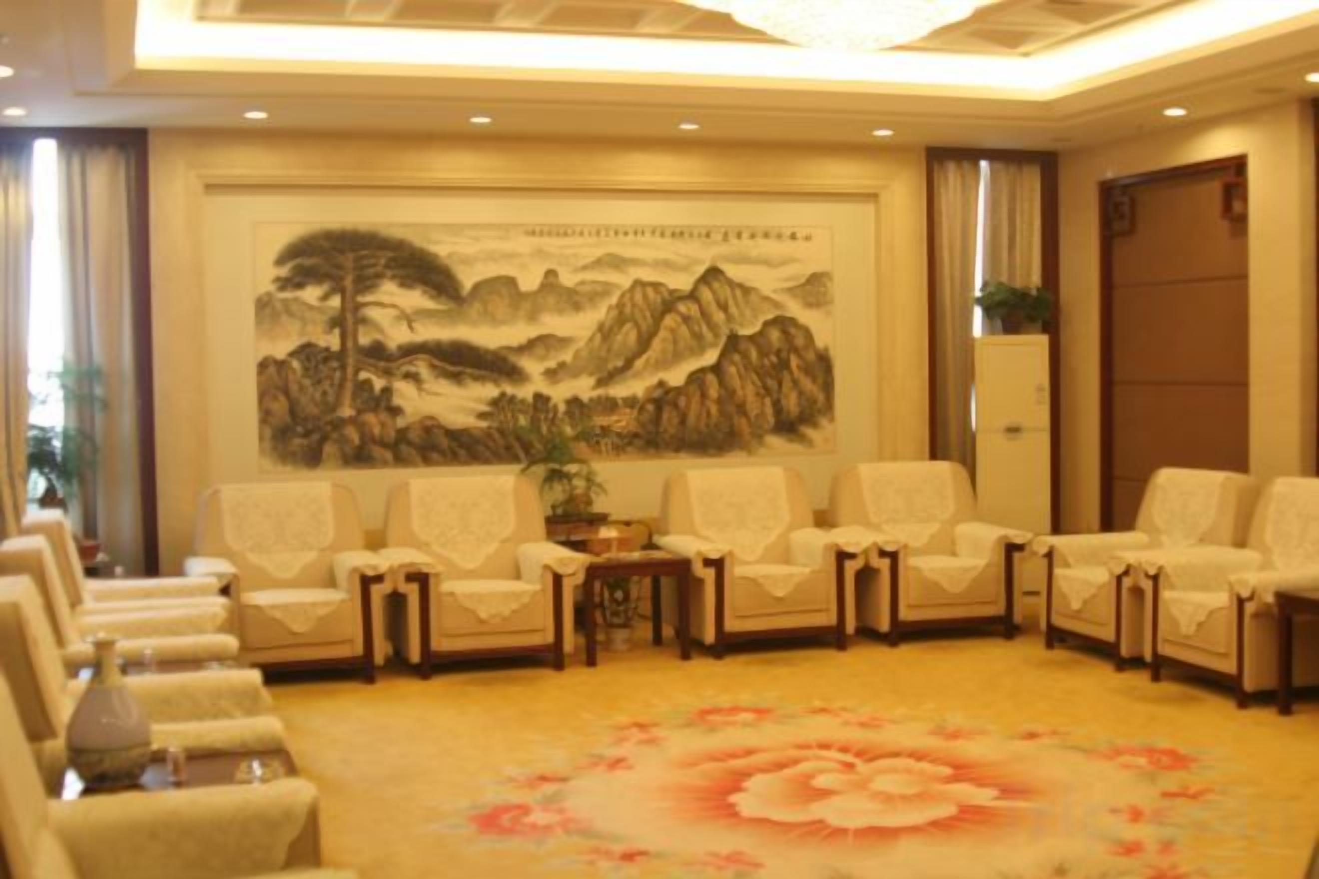 A room with a traditional Chinese landscape painting, multiple seating arrangements, and a floral carpet.