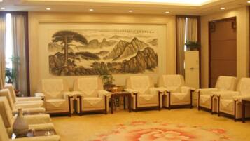 A room with a traditional Chinese landscape painting, multiple seating arrangements, and a floral carpet.