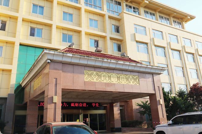 A multi-story building with a prominent entrance, likely a hotel or office building, featuring a tiled roof and a large entrance canopy.