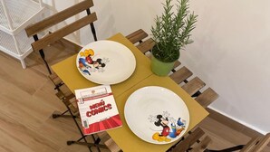 A dining table with two plates featuring cartoon characters, a menu, and a potted plant. - Stay Costa House Naples (Naples)