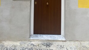A door with a white frame and a wooden door, set in a building with a yellow and grey wall. - Stay Costa House Naples (Naples)