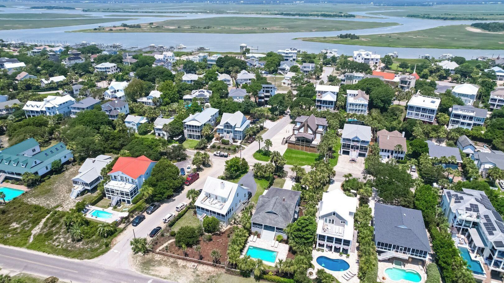Vue aérienne d’un quartier résidentiel avec des maisons, des piscines et un port de plaisance.