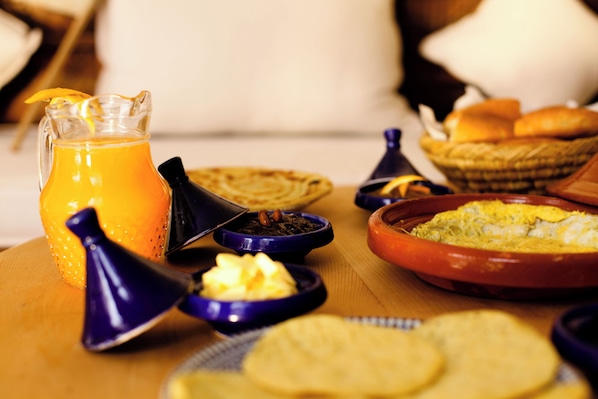 A table with various breakfast items including a pitcher of orange juice, a bowl of eggs, and several small dishes with different foods.