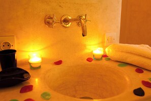 A bathroom sink with a yellow basin, a towel, and candles.
