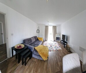 A modern living room with a sofa, a coffee table, a TV, and a patterned rug.