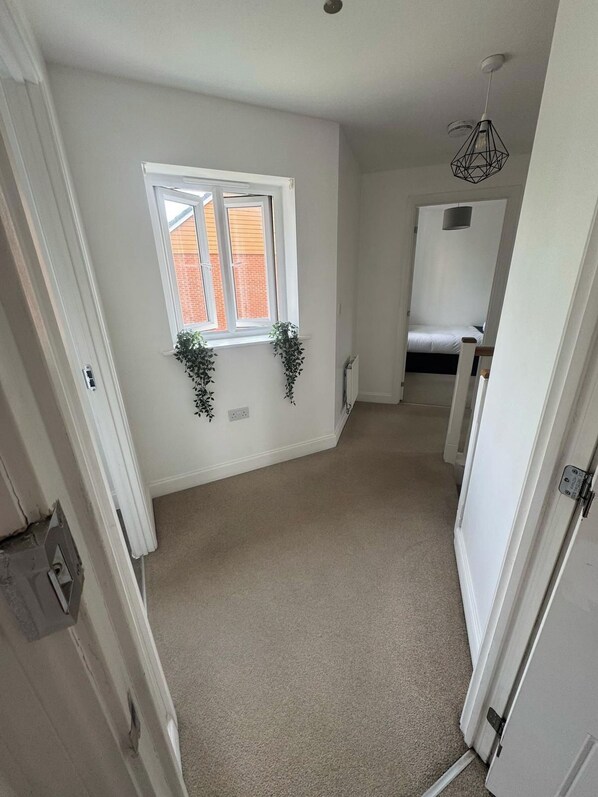 A room with a window, a radiator, a bed, and a hanging light fixture.