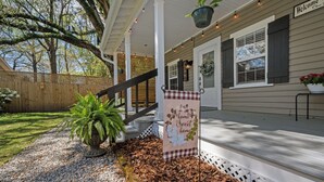 A porch with a welcome sign, a potted plant, and a stone pathway. - Precious 1-bedroom Cottage in Midtown Mobile Recently renovated with fenced yard (Mobile)