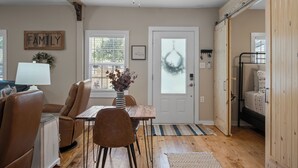 A cozy living room with a dining area, a wooden ceiling, and a door with frosted glass. - Precious 1-bedroom Cottage in Midtown Mobile Recently renovated with fenced yard (Mobile)