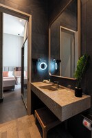 Un baño moderno con un espejo grande, un lavabo y un banco.